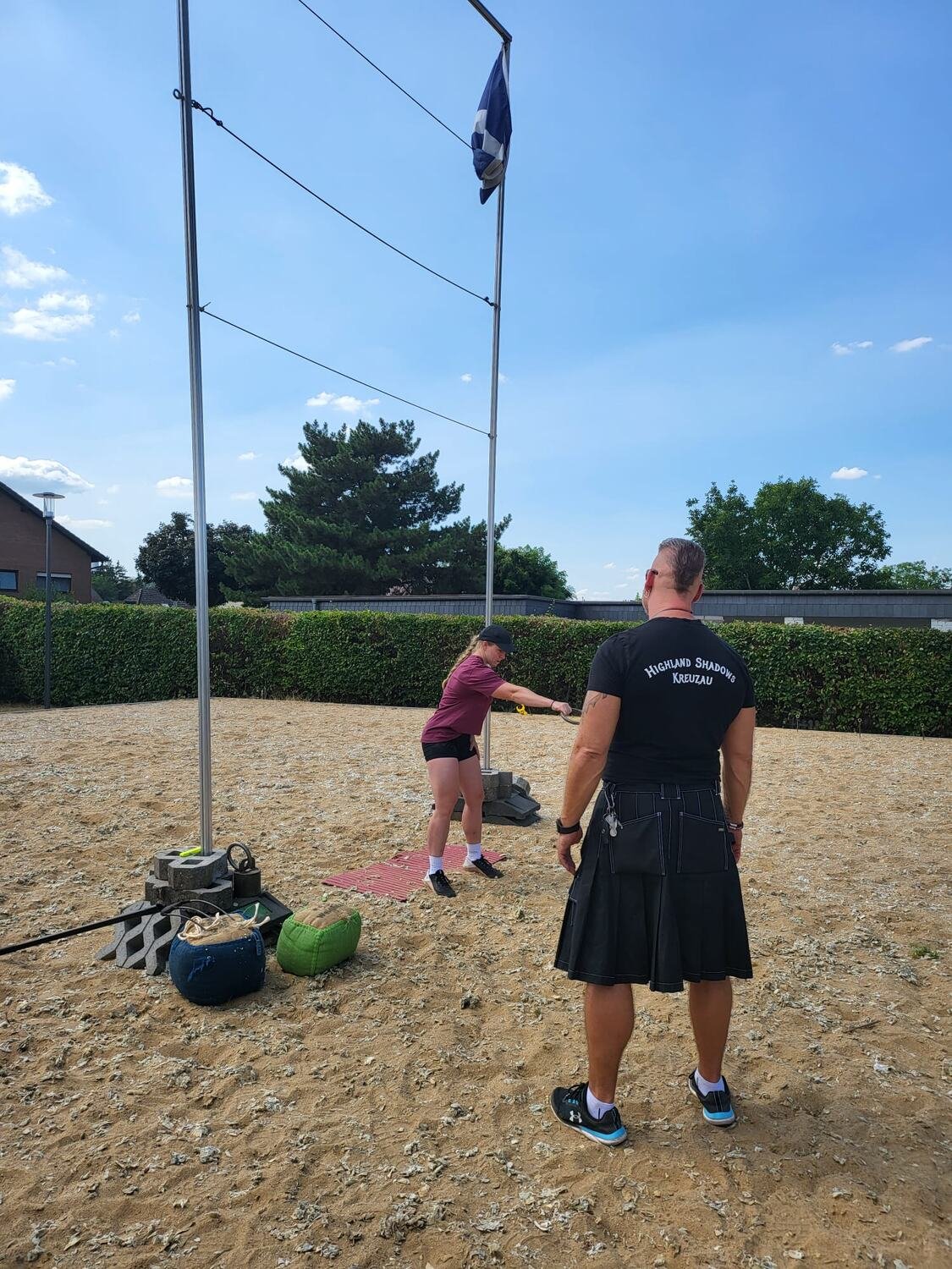Ein Sportler von Highland Shadows Kreuzau im Kilt beobachtet den Versuch an der Hochlatte, im Hintergrund die schottische Flagge