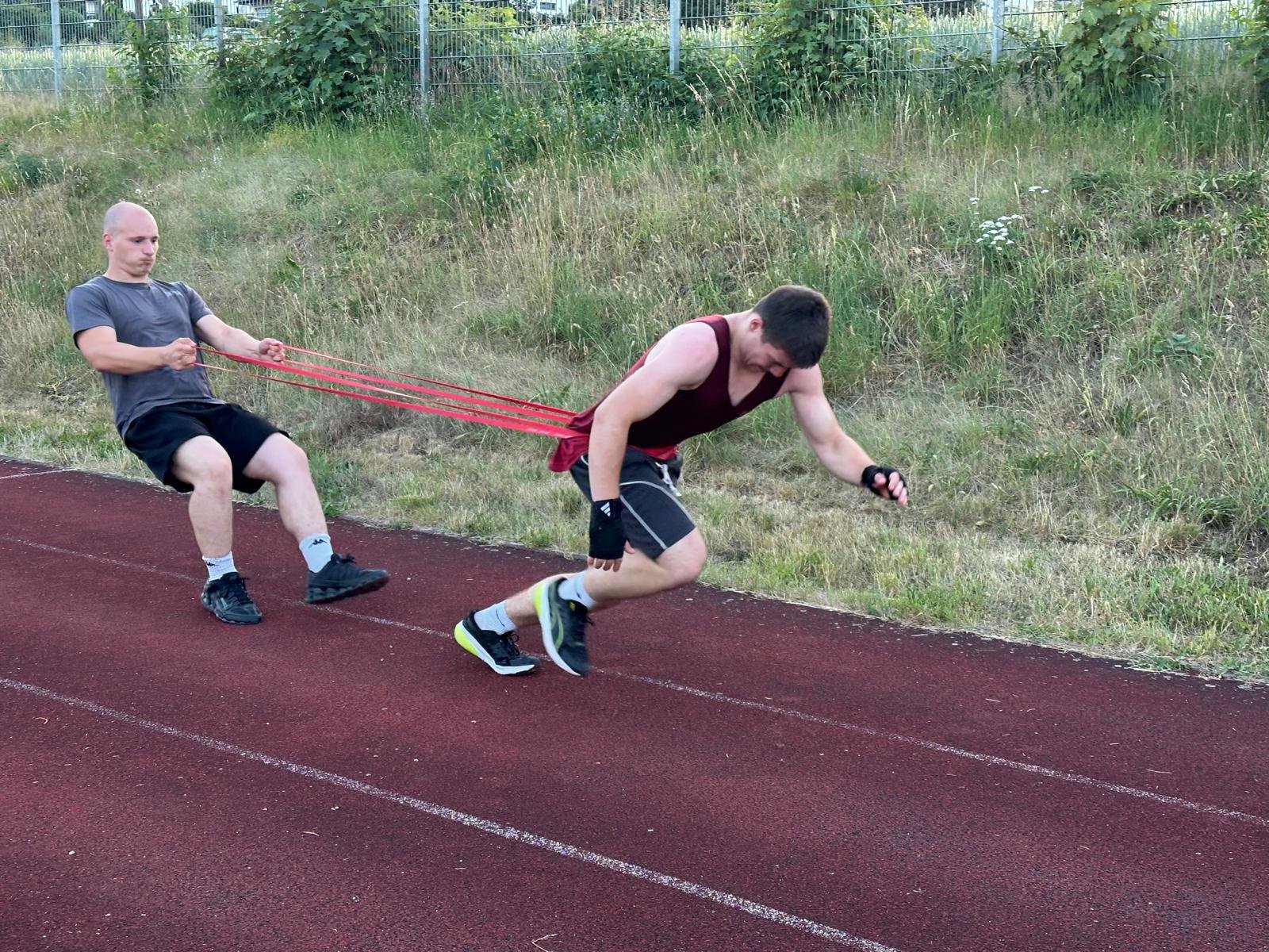 Sprinttraining mit Widerstandsband auf der Laufbahn